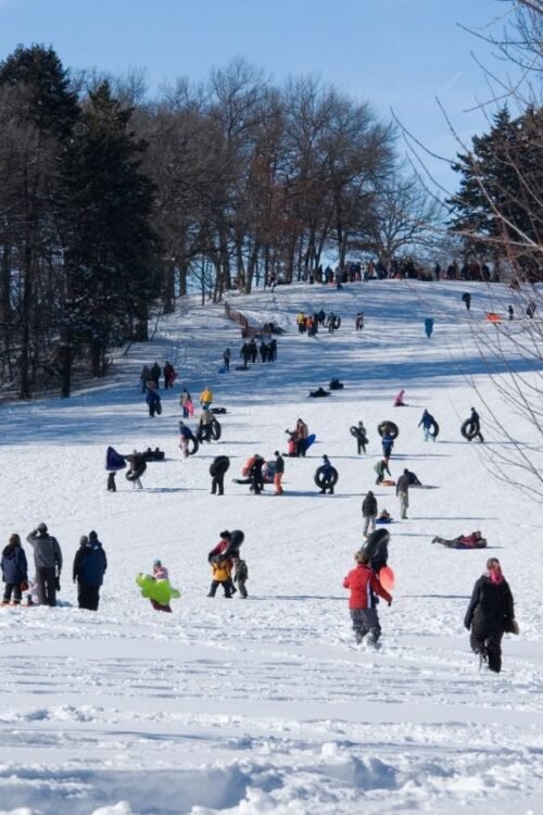 Hometown Christmas bucket list item - sledders play at the local hill covered in snow.