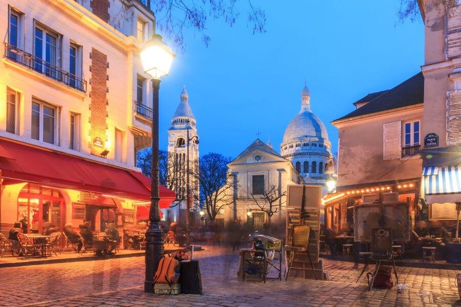 Place du Tertre, Montmartre at night. cafes, painter easel's, with Basilique du Sacré-Cœur de Montmartre in the backgroun