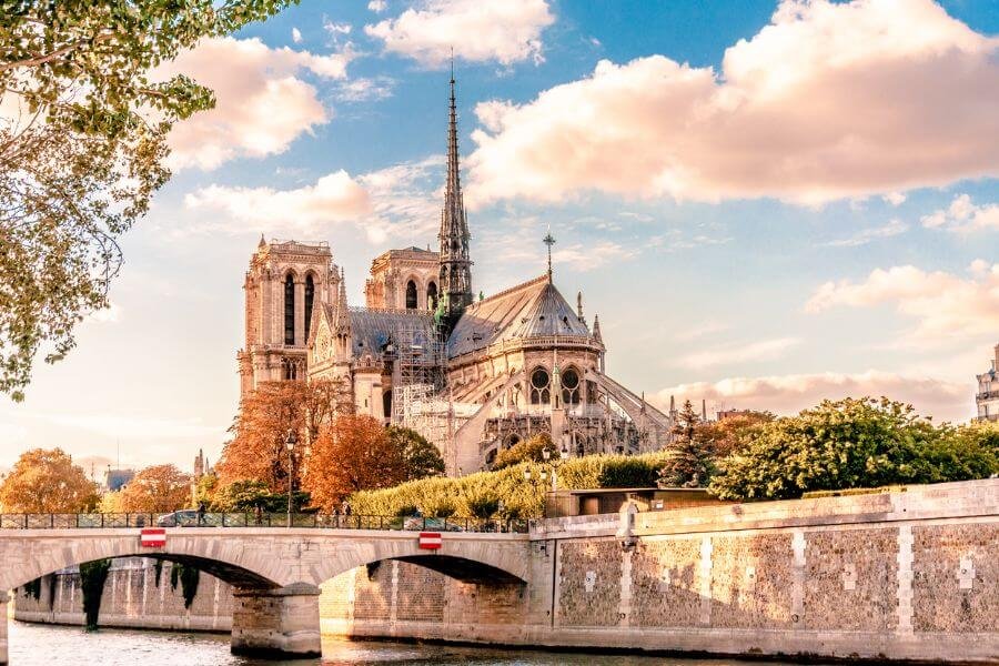 Rear view of Notre-Dame Cathedral of Paris with bridge over Seine River in foreground