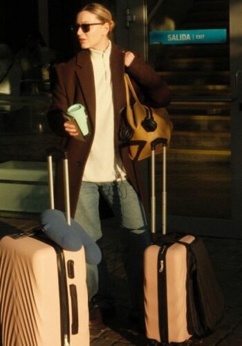 woman at airport with suitcases. winter airport outfits.